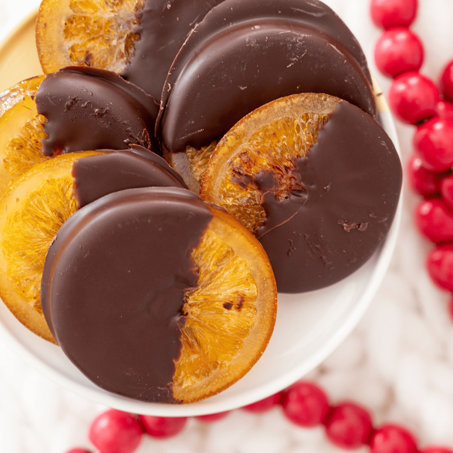 A plate of sunshine! Chocolate Covered Orange Slices displayed on decorative plate. Chocolate and orange make for a beautiful display on your holiday table and a classic holiday gift!