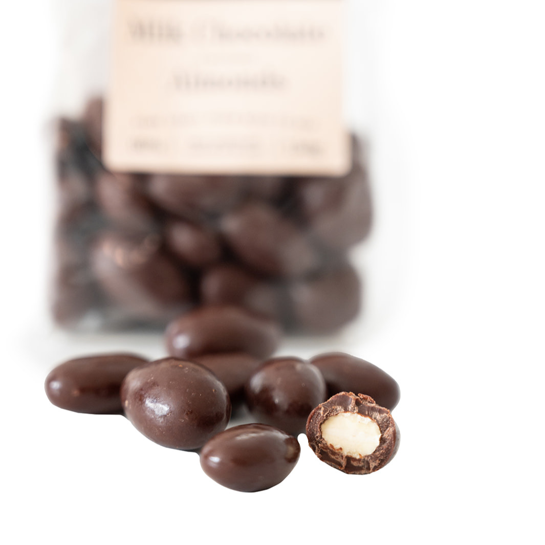 Close up of chocolate covered almond, showing thick layer of rich milk chocolate and roasted almond center