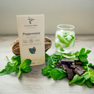 Hummingbird Chocolate Maker Peppermint 60g Chocolate Bar arranged with fresh mint, dark chocolate pieces, and a glass of minty ice water