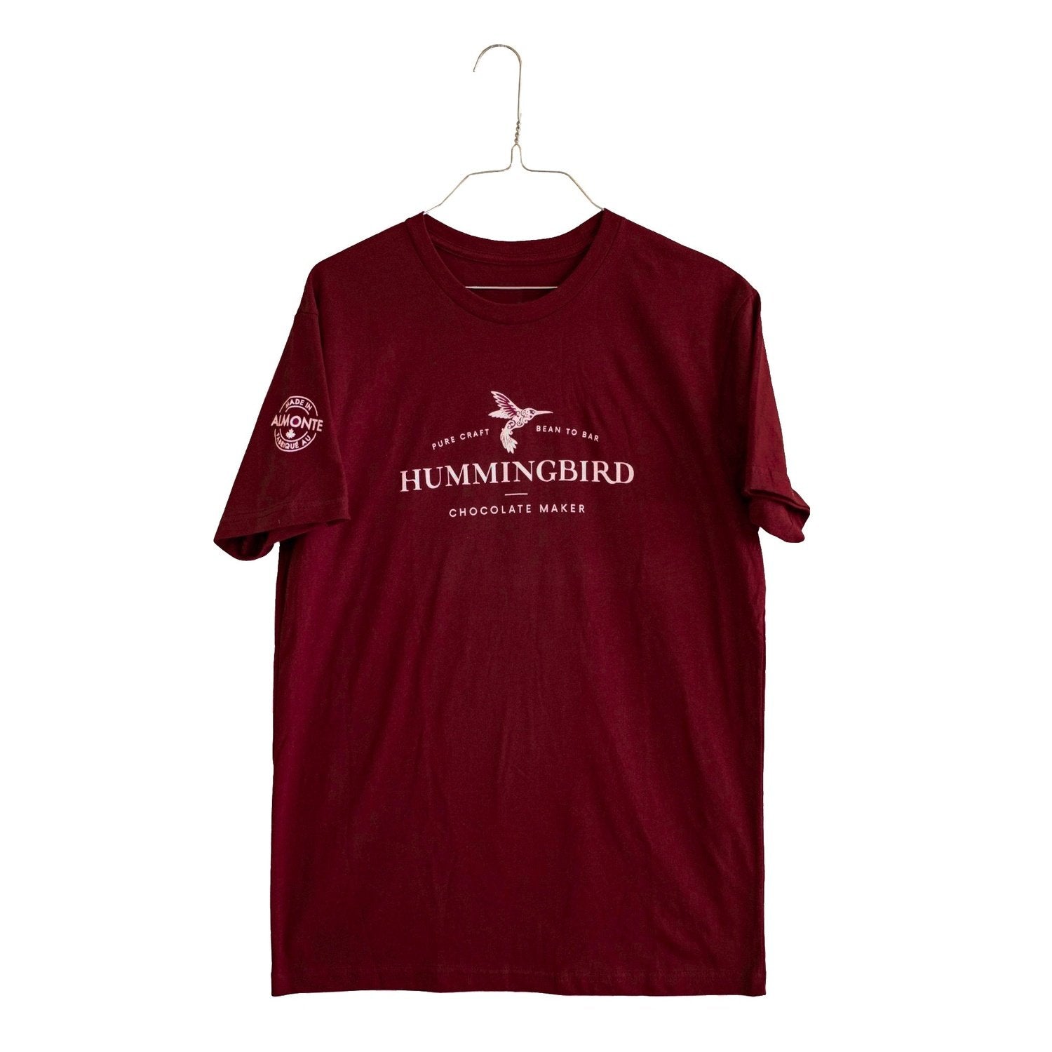 Maroon unisex t-shirt printed with Hummingbird Chocolate Maker logo on front chest and Made in Almonte logo on the right arm